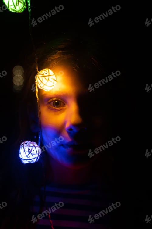 Preview: portrait of a girl with a garland near her face, glowing with colorful multicolored lights at night