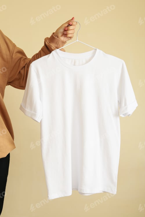 Preview: Woman hold hanger with blank white t-shirt on beige background