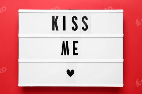 Preview: Light box with phrase Kiss Me on red background, top view