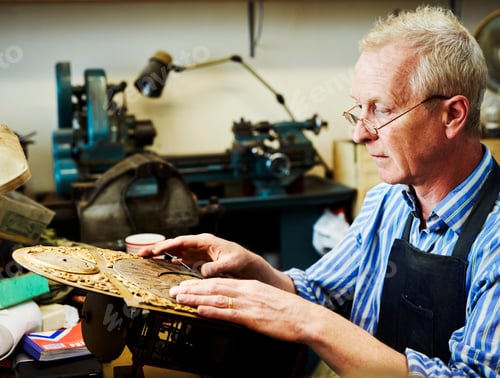 Preview: A clock maker adjusting the hands on the face of an antique clock.