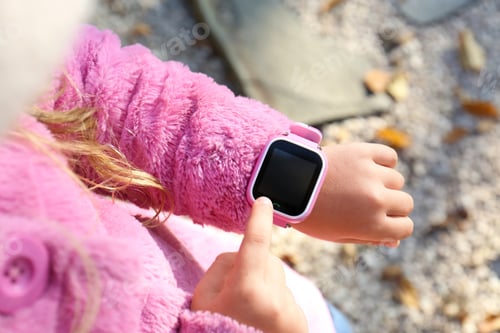 Preview: Little girl using smart watch outdoors, closeup