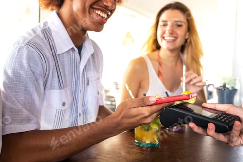 Preview: Close-up of man paying bill at beach bar with phone. Black male paying drinks with mobile phone.
