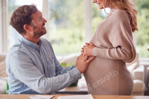 Preview: Close Up Of Couple With Man Touching Pregnant Womans Stomach As She Stands Next To Him