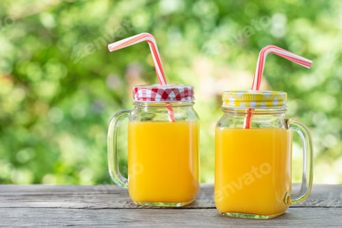 Preview: Orange juice in mason jars with straws on wooden table