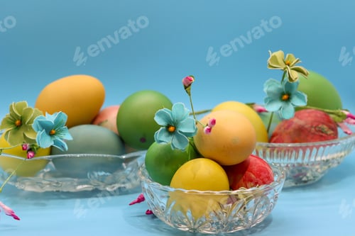 Preview: Softly colored Easter eggs in crystal dishes with Spring flowers against turquoise background.