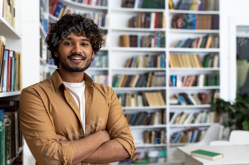 Preview: Confident young man with arms crossed standing in a library