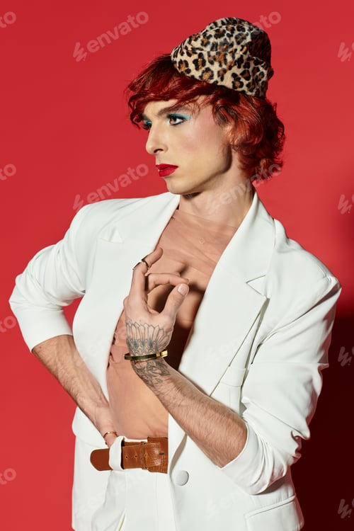 Vista previa: A young man poses confidently in stylish attire against a vibrant red background.