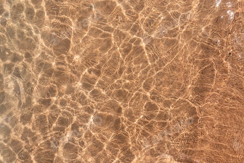 Preview: Beautiful yellow background of the beach with transparent water near the sea, top view. Summer rest
