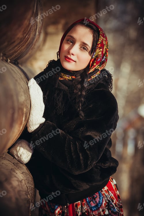 Preview: Russian woman beautiful in the dress and the fur coat in the winter near the old hut. Girl with