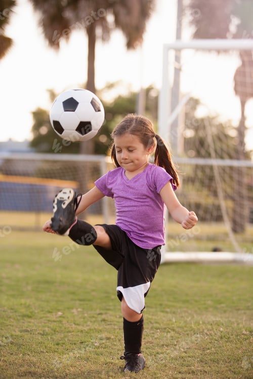 Preview: Girl kicking football on practice pitch