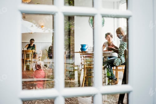 Preview: View through a window into a cafe, people sitting at tables.