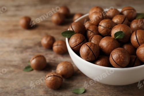 Preview: Bowl with organic Macadamia nuts and space for text on wooden background
