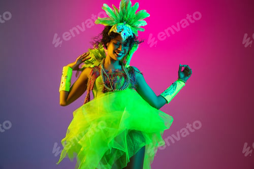 Preview: Beautiful young woman in carnival and masquerade costume on gradient studio background in neon light