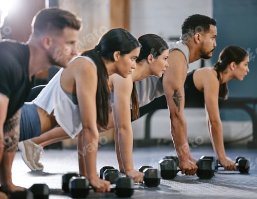 Preview: Diverse group of active young people doing plank hold and push up exercises with dumbbells while tr