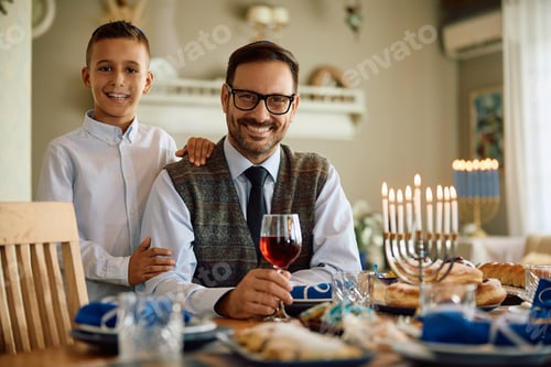 Preview: Happy Jewish father and son on Hanukkah at home looking at camera.