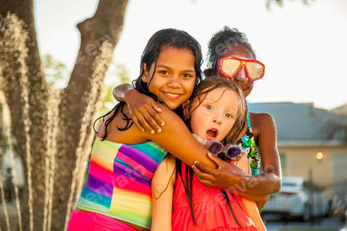 Preview: Portrait of three girls hugging in garden