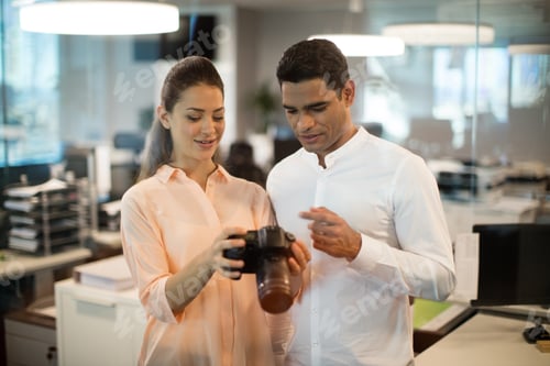 Preview: Businesswoman showing camera to colleague in office