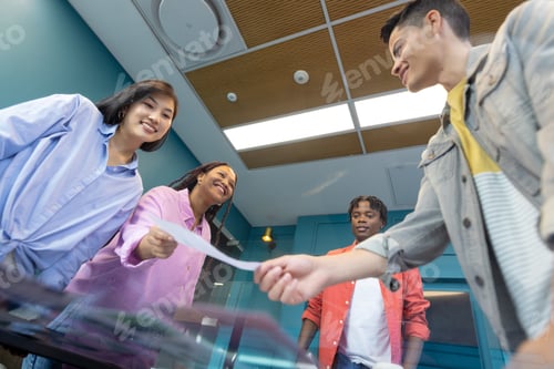 Preview: Young, diverse colleagues sharing documents and smiling in a startup collaboration