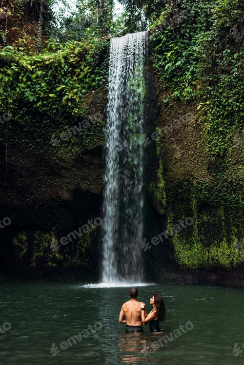 Preview: Lovers at the waterfall. Couple admiring a beautiful waterfall in Indonesia