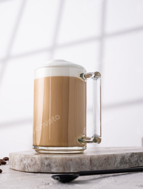 Preview: Cappuccino or latte with milk foam in a cup on marble background with morning shadow. Hero view