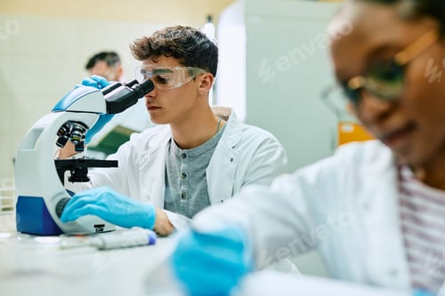 Preview: Young science student looking through microscope during a research in laboratory.