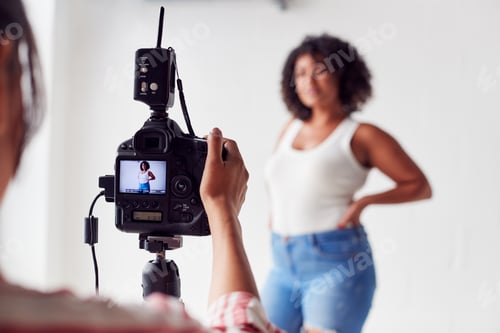 Preview: Female Photographer In Digital Studio Shooting Images On Camera Tethered To Laptop Computer