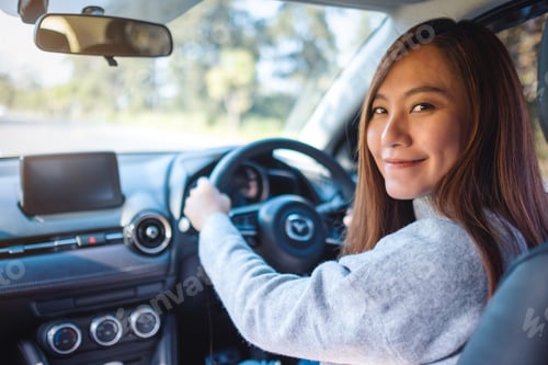 Preview: Closeup image of an asian woman holding steering wheel while driving a car