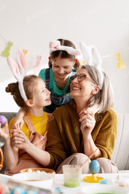 Preview: Smiling grandmother and granddaughters celebrating Easter holiday and decorating eggs