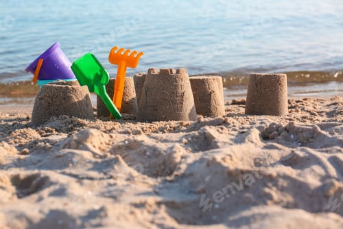 Preview: Little sand figures and plastic toys on beach near sea
