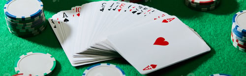 Preview: High angle view of pack of cards with casino chips on green background, panoramic shot