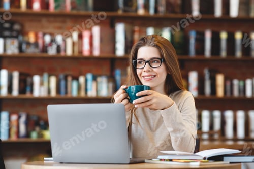 Preview: Happy young girl working on laptop computer, sitting in cafe