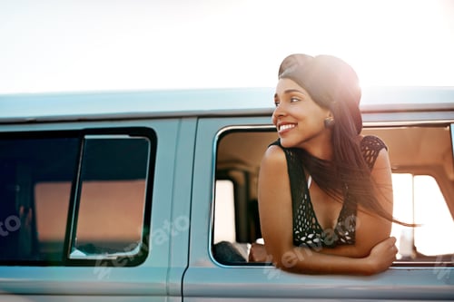 Preview: Shot of a happy young woman leaning out of the window during a road trip