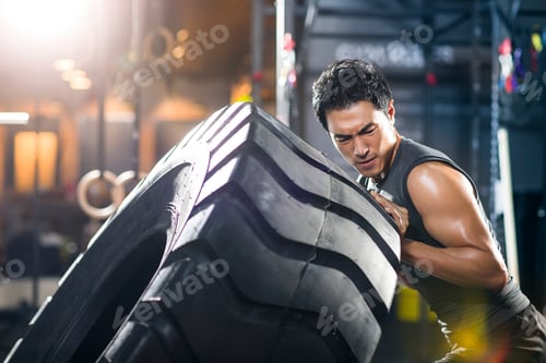 Preview: Young man pushing large tire in crossfit gym