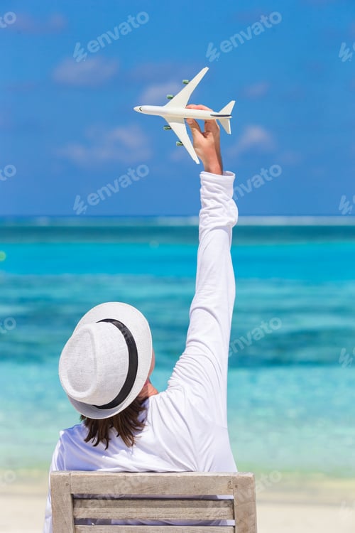 Preview: Young man with miniature of an airplane at tropical beach