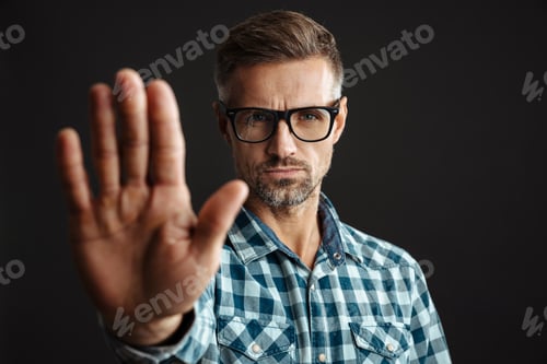 Preview: Serious grey-haired man showing stop gesture