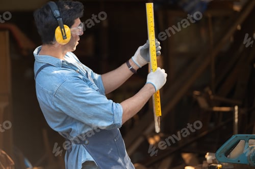 Preview: Portrait of a carpenter holding a spirit level in his workshop.