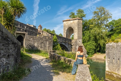 Preview: Tourist admiring the medieval bridge and fortified walls of sauveterre de bearn in france