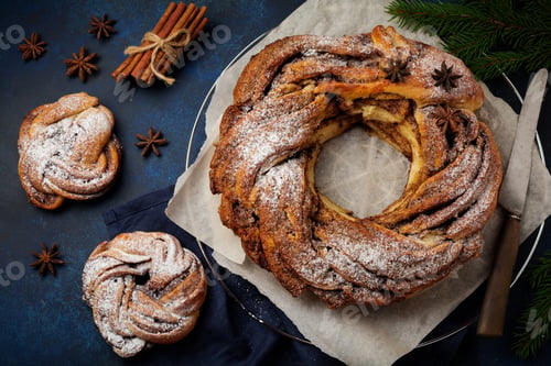 Preview: Christmas pie roll with cinnamon and powdered sugar on a dark old concrete or stone background. Sele