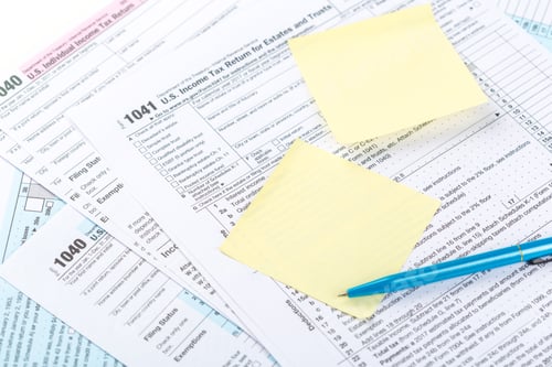 Preview: Documents for US income tax filing with notes and pen on the table