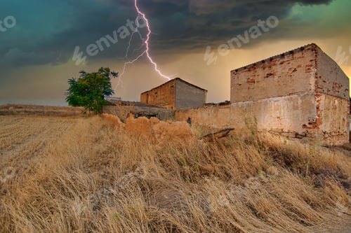 Preview: Couple of houses on a dry grass field with lightning hitting one of them