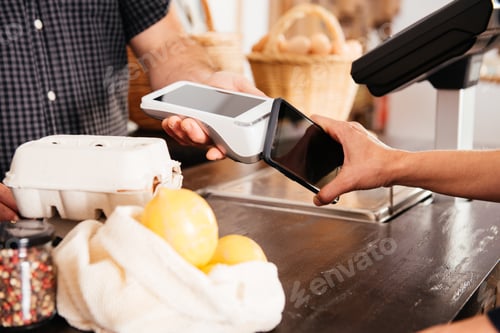 Preview: Close-Up View of Customer Using Smartphone for Contactless Payment at Grocery Counter