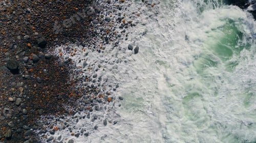 Preview: Ocean foam rolling stony beach drone view. Stormy rough waves foaming seashore