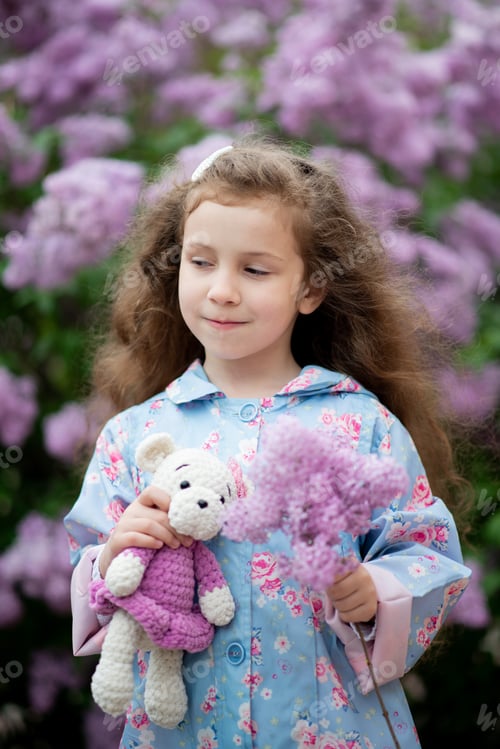 Preview: A cute girl next to a bush of blooming lilacs.
