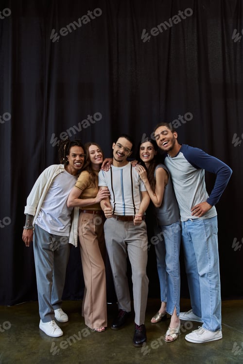 Preview: full length of happy and stylish multicultural team posing on black backdrop in office, group photo