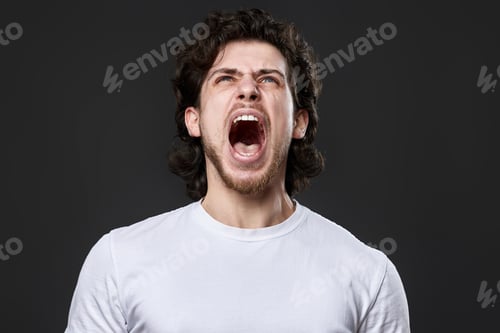 Preview: annoyed angry curly bearded man on dark gray studio background