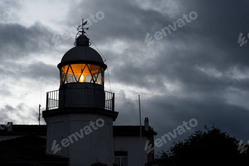 Preview: Shining lighthouse against cloudy sky