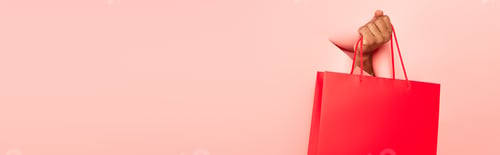 Preview: partial view of african american man holding shopping bag on ripped pink background, banner