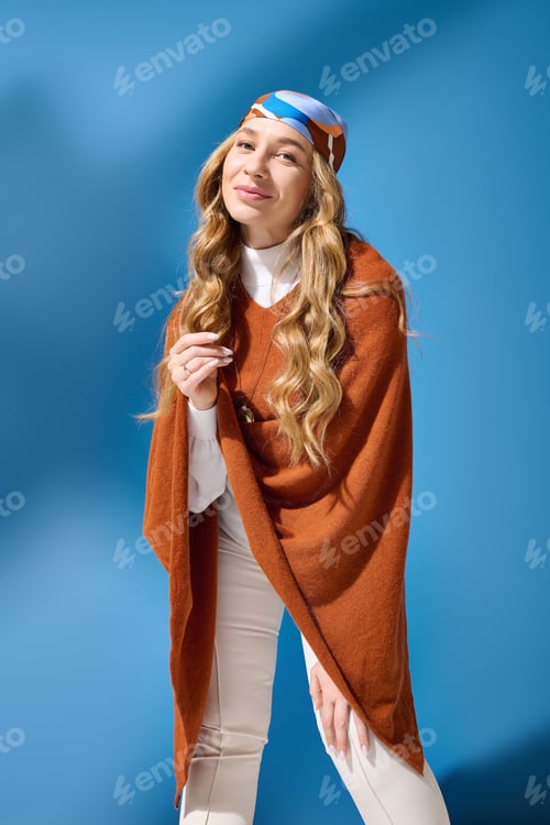 Preview: Young beautiful plus size woman poses elegantly in stylish attire against a vibrant blue backdrop