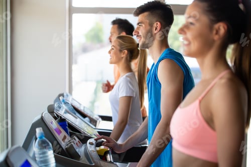 Preview: Group of happy fit young people running on a treadmill in health club