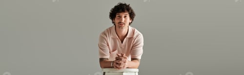 Preview: Stylish young man showcasing modern fashion with confidence in a minimalist studio setting